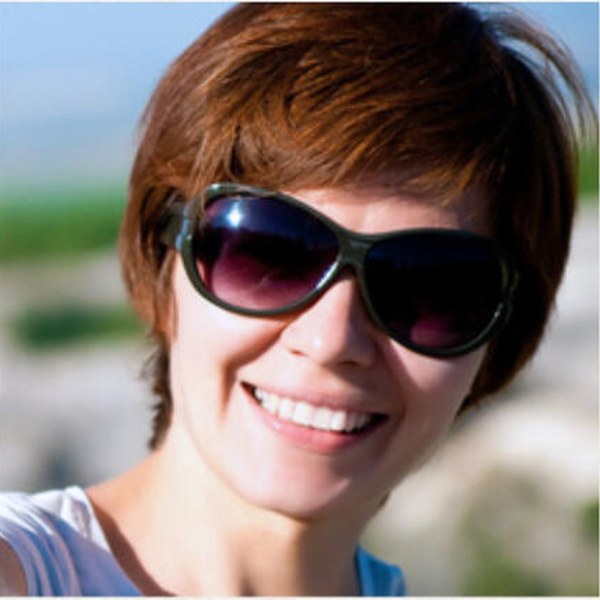 A woman smiling outdoors on a bright day
