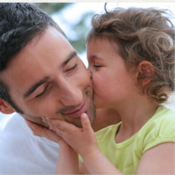 A young child kissing her father on the cheek
